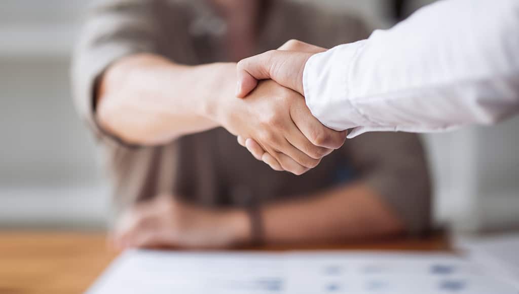 Wholesale real estate syndication partners shaking hands.